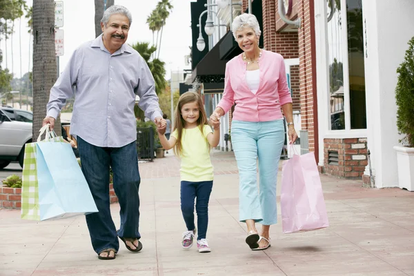 Abuelos con nieta llevando bolsas de compras — Foto de Stock