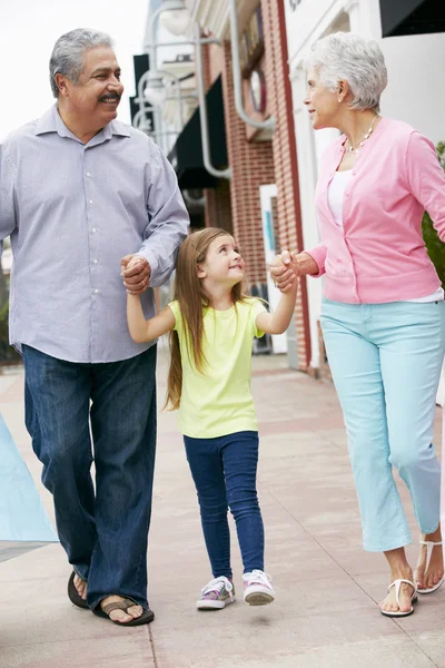 Abuelos con nieta llevando bolsas de compras — Foto de Stock