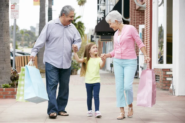 Abuelos con nieta llevando bolsas de compras — Foto de Stock