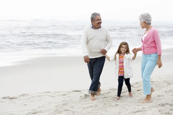 Grands-parents avec petite-fille marchant le long de la plage — Photo