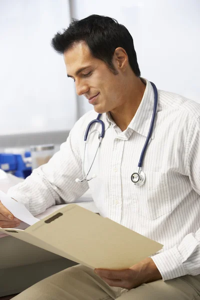 Männlicher Arzt liest Patientennotizen — Stockfoto