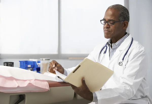 Männlicher Arzt liest Patientennotizen — Stockfoto