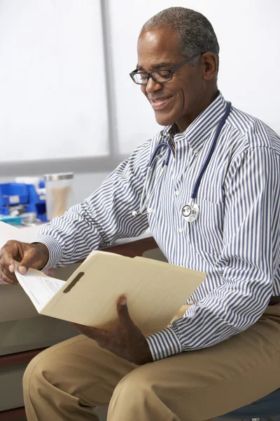 Männlicher Arzt liest Patientennotizen — Stockfoto