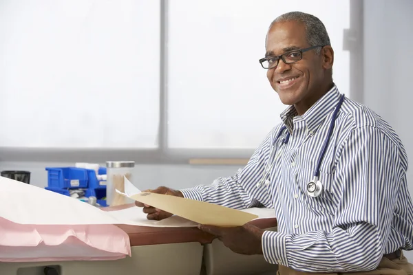 Männlicher Arzt liest Patientennotizen — Stockfoto
