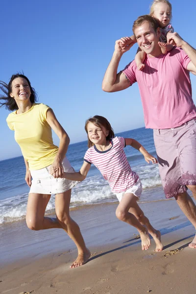 Family Running Along Beach Stock Photo