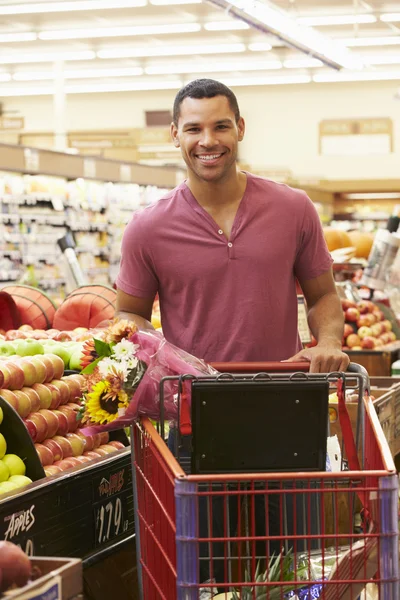 Mann schiebt Einkaufswagen in Supermarkt — Stockfoto