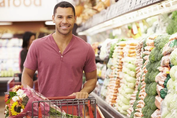 Mann schiebt Einkaufswagen in Supermarkt — Stockfoto