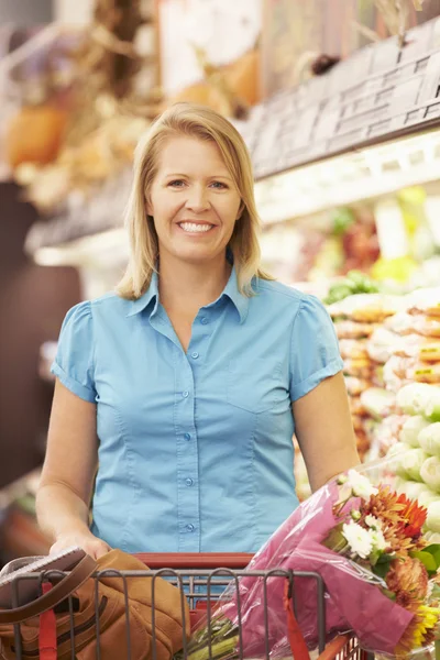 Женщина толкает тележку в супермаркете — стоковое фото