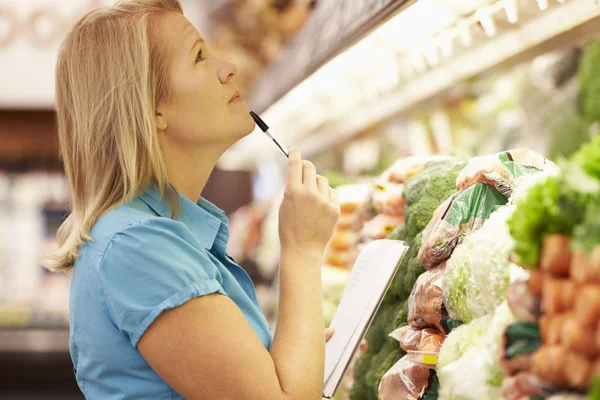 Een vrouw die boodschappenlijstje leest — Stockfoto