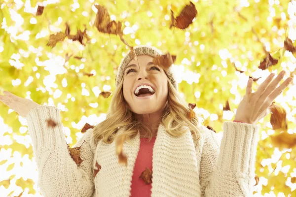 Vrouw gooien herfst bladeren — Stockfoto