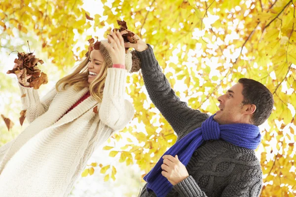 Pareja lanzando hojas en el jardín — Foto de Stock