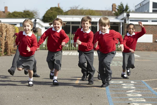 Alumnos de primaria corriendo en el patio de recreo — Foto de Stock