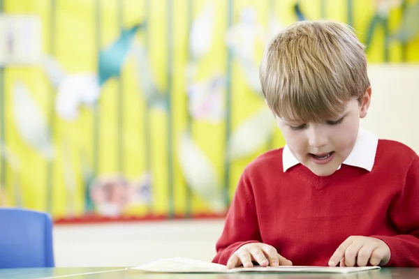 Männlicher Schüler liest Buch am Tisch — Stockfoto