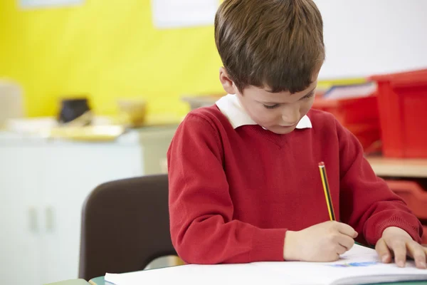 Männlicher Schüler übt Schreiben am Tisch — Stockfoto