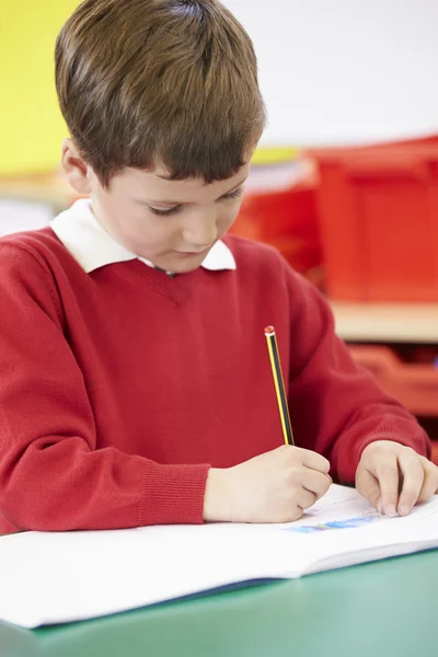 Männlicher Schüler übt Schreiben am Tisch — Stockfoto