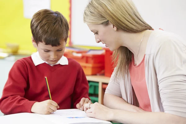 Leraar met leerling beoefenen schrijven aan balie — Stockfoto