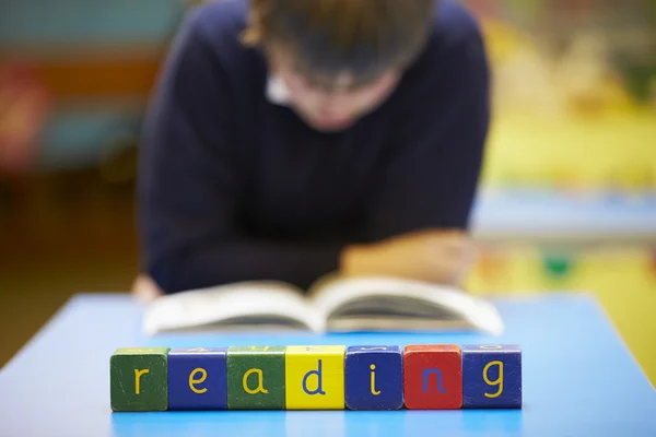 Word "Reading" In Blocks With Pupil Behind — Stock Photo, Image