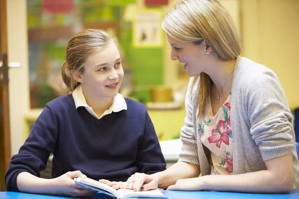 Lehrerin mit Schüler liest am Schreibtisch — Stockfoto