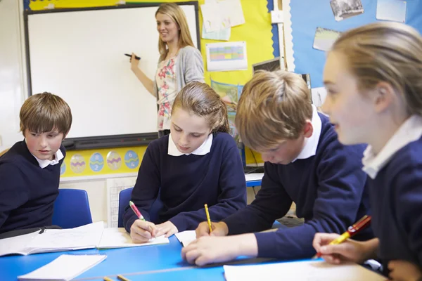 Leerlingen zitten als leraar Stands door Whiteboard — Stockfoto