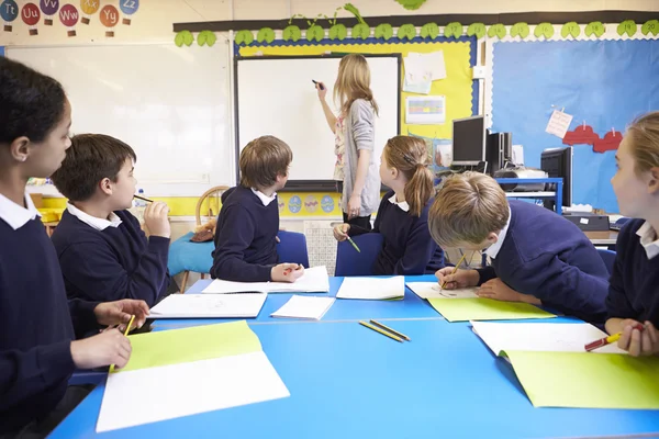 Leerlingen zitten als leraar Stands door Whiteboard — Stockfoto