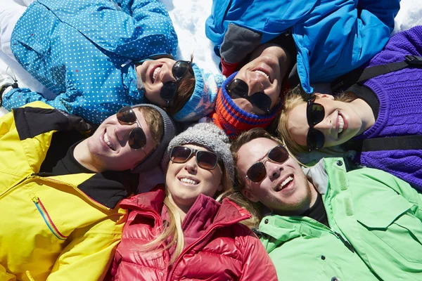 Amigos que yacen en la nieve en vacaciones de invierno — Foto de Stock