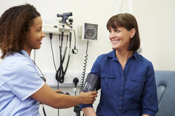 Sjuksköterska med patientens blodtryck — Stockfoto