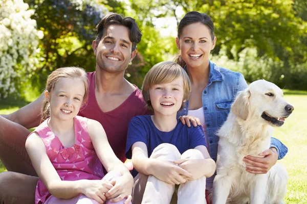 Familia con perro relajante en el jardín Fotos De Stock