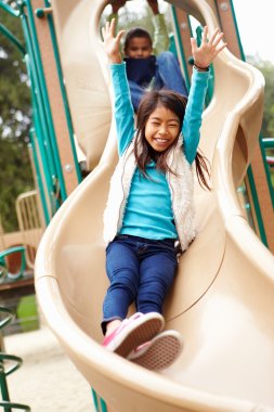Young Girl Playing On Slide In Playground clipart