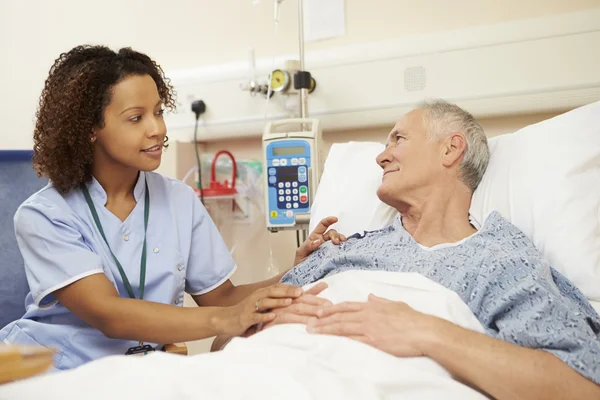 Enfermera sentada junto a la cama del paciente en el hospital — Foto de Stock