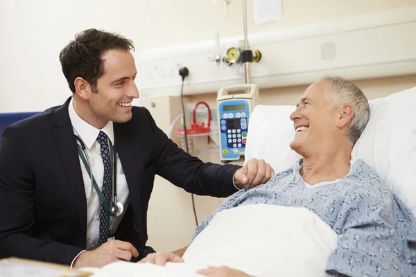 Dokter zitten door Bed van de patiënt In het ziekenhuis — Stockfoto