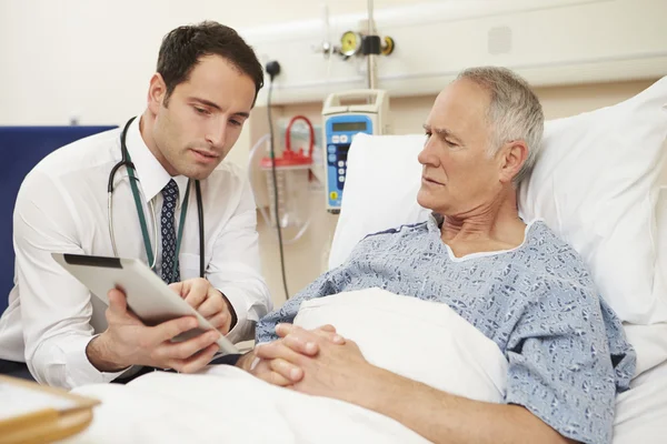 Médico sentado junto a la cama del paciente con tableta digital — Foto de Stock