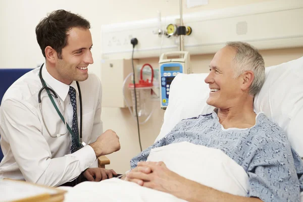 Lekarz siedzi przy łóżku chorego w szpitalu — Zdjęcie stockowe