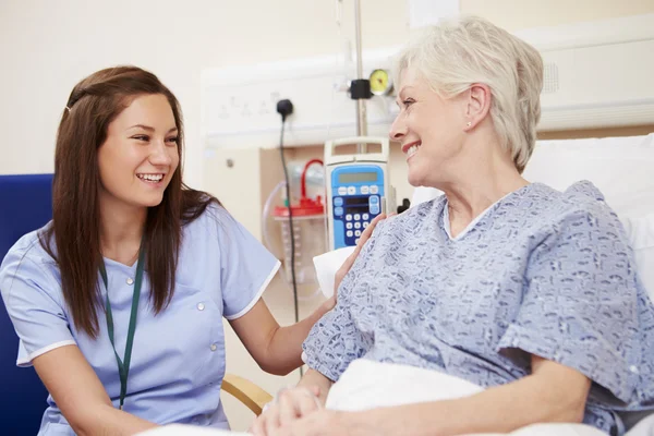 Sjuksköterska sitter vid patientens säng på sjukhuset — Stockfoto