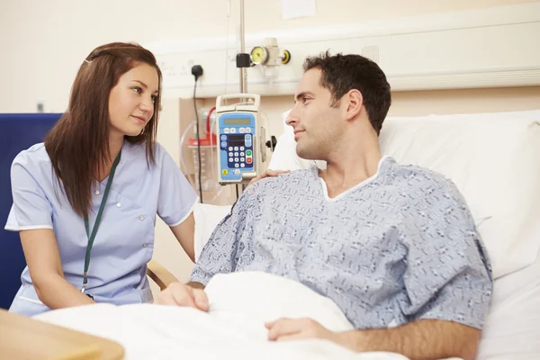 Enfermera sentada junto a la cama del paciente en el hospital — Foto de Stock