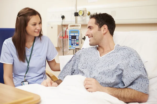 Медсестра, сидящая у кровати пациента в больнице — стоковое фото