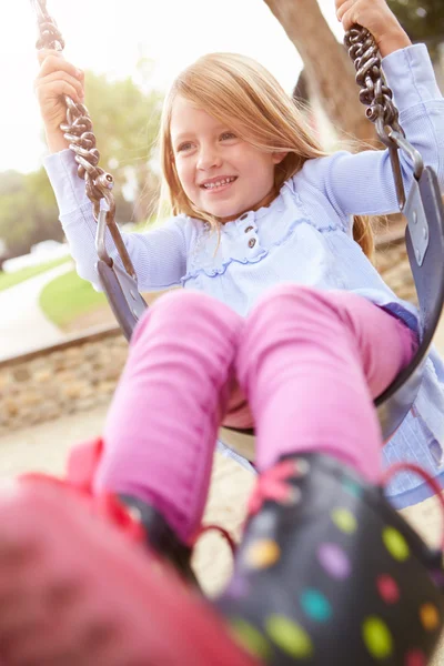 Giovane ragazza giocare su swing in parco giochi — Foto Stock