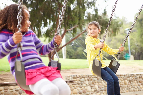 Meisjes spelen op schommel In Speeltuin — Stockfoto