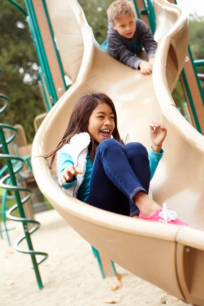 Chica joven jugando en la diapositiva en el patio de recreo —  Fotos de Stock