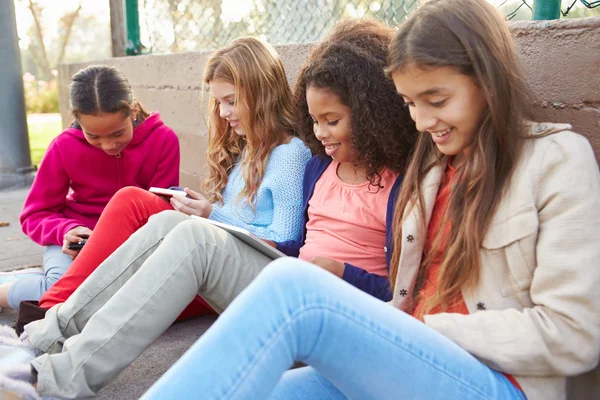 Niñas usando dispositivos digitales en el parque — Foto de Stock