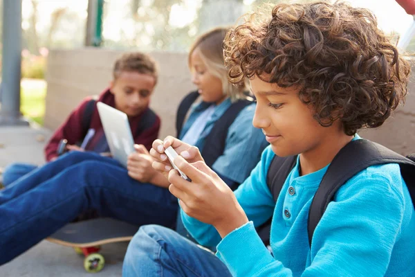 Niños usando dispositivos digitales en el parque — Foto de Stock