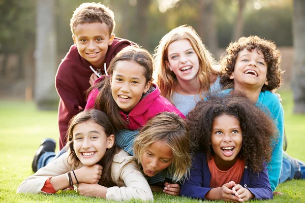 Groep kinderen liggen op gras In Park — Stockfoto