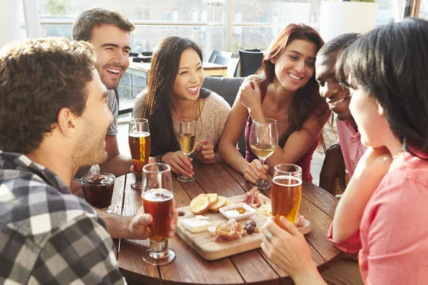 Друзья наслаждаются напитками и закусками в баре — стоковое фото