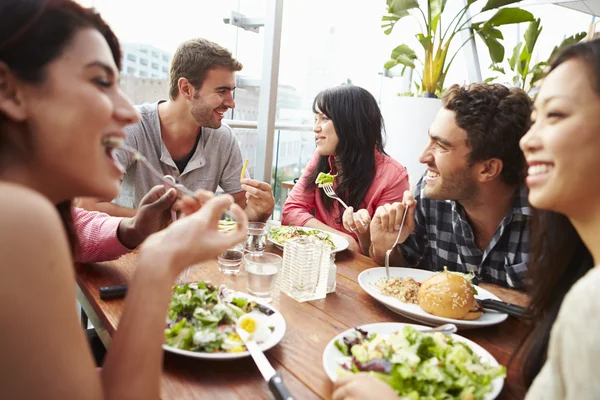 Skupina přátel, užívat si jídlo v restauraci — Stock fotografie