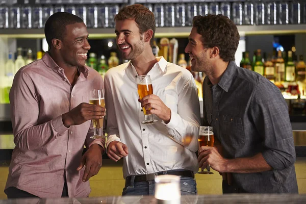 Três amigos do sexo masculino desfrutando de bebidas no bar — Fotografia de Stock