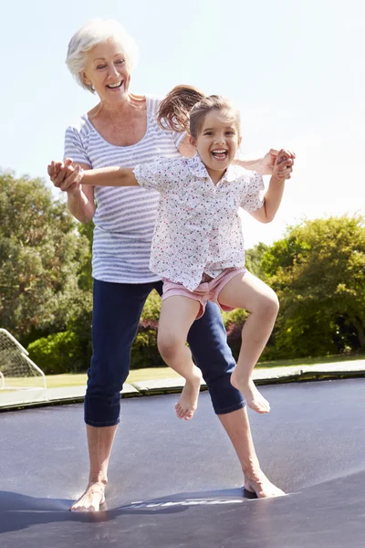 Mormor och barnbarn studsande på studsmatta — Stockfoto