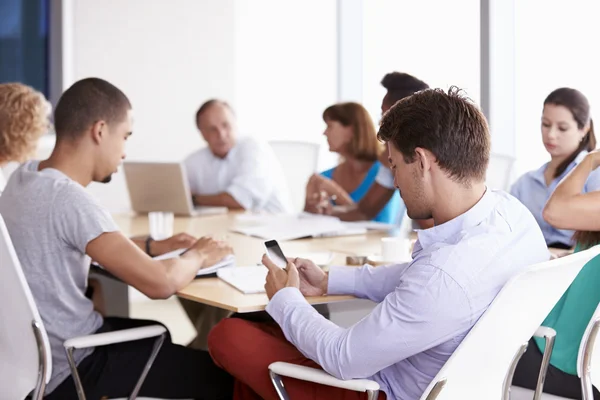 Zakenman met behulp van mobiele telefoon in vergadering — Stockfoto