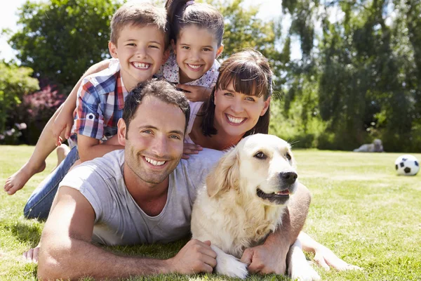 Familie entspannen im Garten mit Hund lizenzfreie Stockbilder