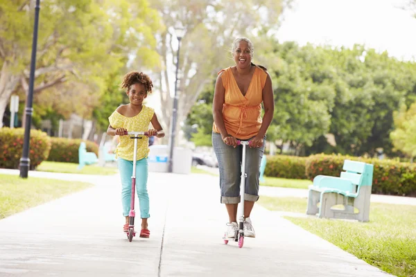 Abuela y nieta montando scooters en el parque —  Fotos de Stock