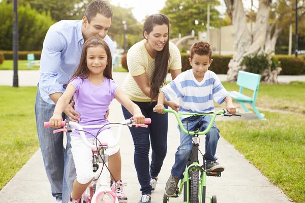 Pais ensinando as crianças a andar de bicicleta no parque — Fotografia de Stock