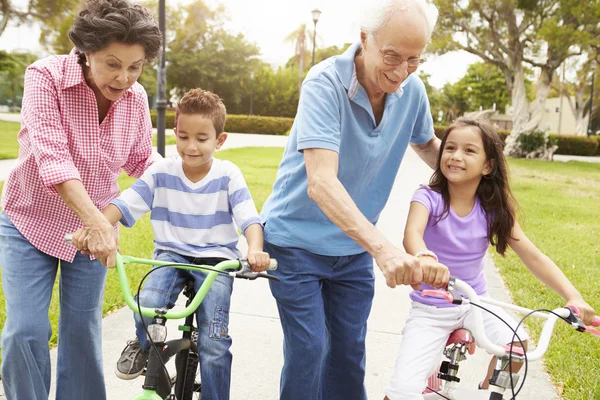 Grootouders kleinkinderen lesgeven aan rit fietsen — Stockfoto